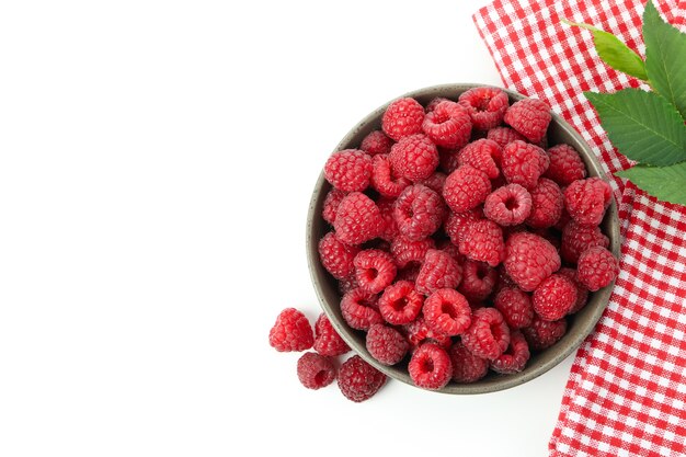 Rote saftige Himbeeren in Schüssel und Küchentuch, isoliert auf weißem Hintergrund.