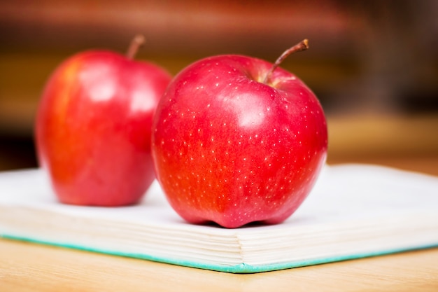 Rote saftige Äpfel liegen auf einem Buch im Büro