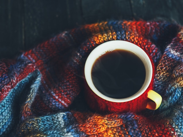 Rote Schale Espressokaffee auf dem Tisch eingewickelt in einem hellen bunten Herbstschal