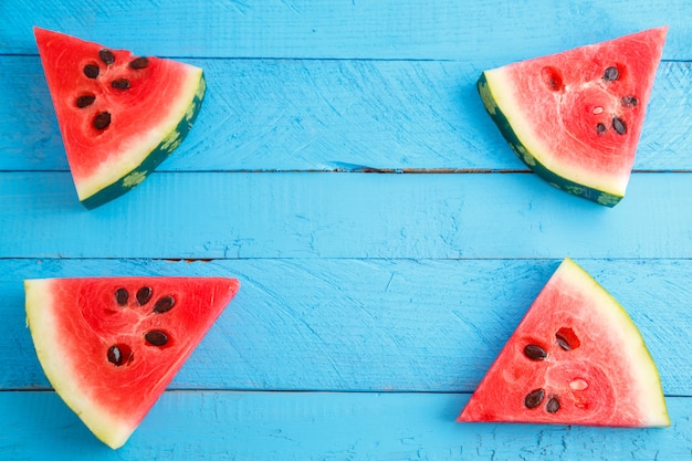 Rote scharlachrote Wassermelonenstücke auf blauem hölzernem Weinlesehintergrund.