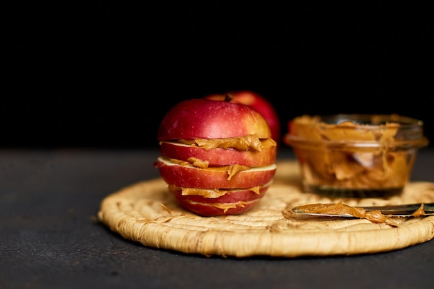 Rote Scheiben Sandwich oder Burger aus Apfel mit Erdnussbutter auf dunklem Hintergrund