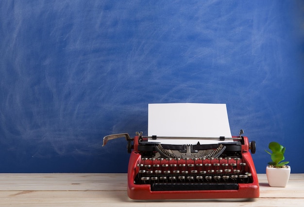 Rote Schreibmaschine am Arbeitsplatz des Verfassers auf blauem Tafelhintergrund