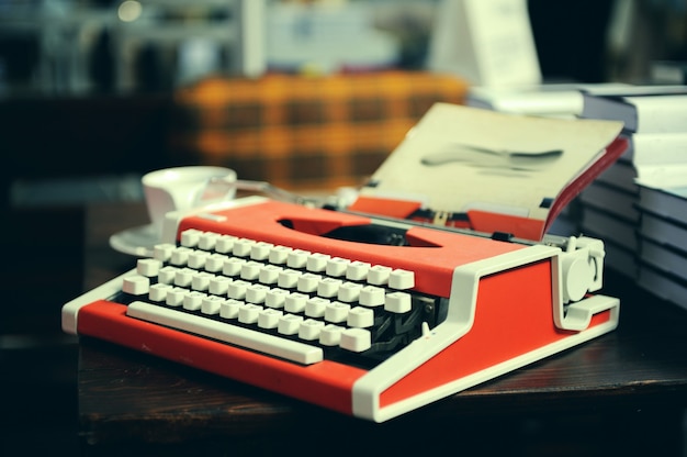 Rote Schreibmaschine mit Blatt Papier auf Holztisch