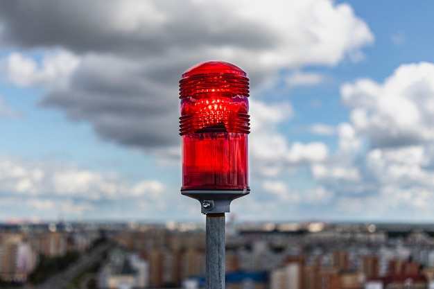 Rote Signalleuchte. Signalleuchten auf dem Dach eines mehrstöckigen Gebäudes vor dem Hintergrund von Stadtgebäuden. Sicherheit im Luftverkehr.