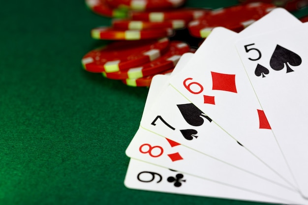 Rote spielende Chips und Karten am Pokertisch