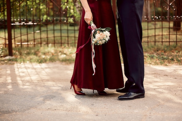 Rote Stöckelschuhe und Brautjungfernkleid mit Blumenstrauß