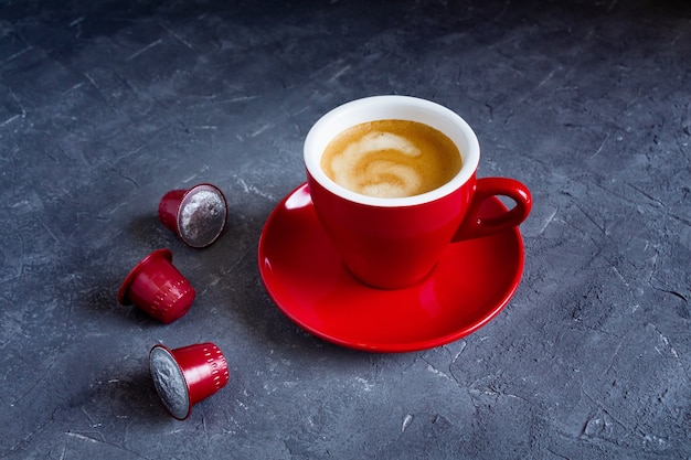 Rote Tasse heißen Cappuccino mit Kaffeekapseln.