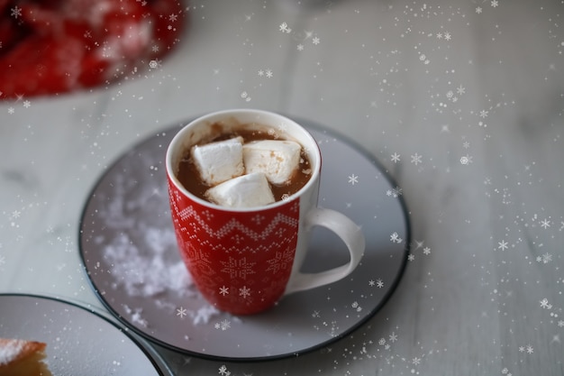 Rote Tasse mit heißem Getränk und Marshmallow im Inneren