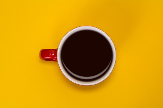 Rote Tasse mit Kaffee auf gelbem Hintergrund Ansicht von oben
