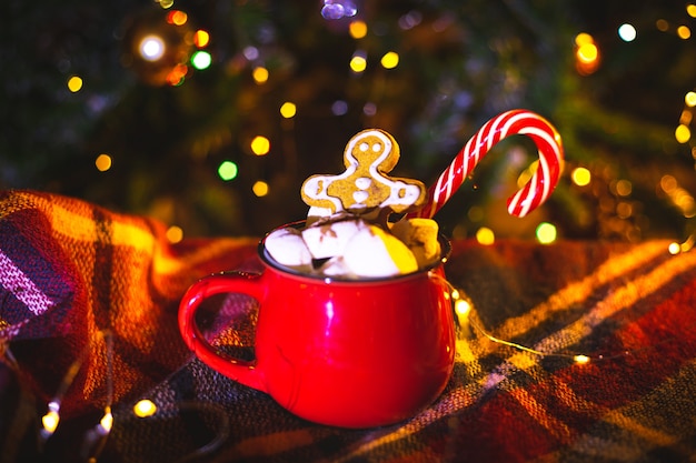 Rote Tasse mit Kakao und Marshmallows. Hausgemachter Lebkuchen. Traditionelle Weihnachtsdekoration.