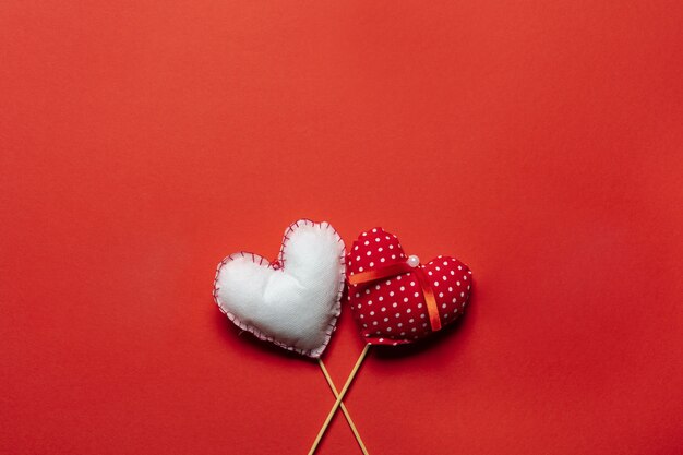 Rote Textilherzen auf Holzstöcken für Valentinstaghintergrund.