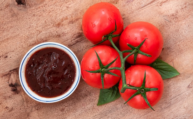 Foto rote tomate mit tomatensauce auf holzbrett