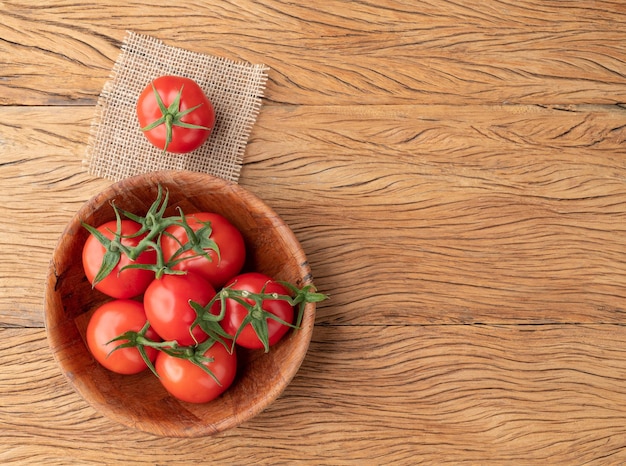 Rote Tomaten auf einer Schüssel über Holztisch mit Kopienraum