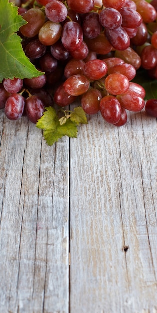 Rote Trauben mit Blättern auf einem alten Holztisch schließen oben