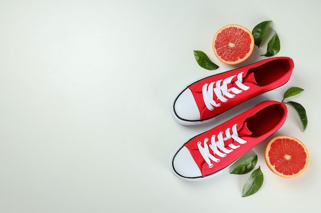 Rote Turnschuhe und Grapefruit mit Blättern auf weißem Hintergrund