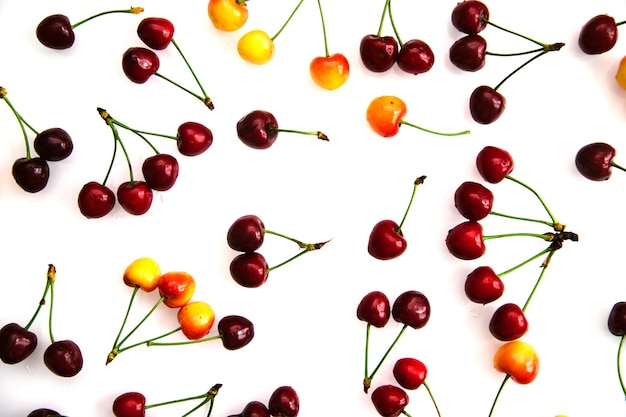 Rote und gelbe reife Kirschen. Die Beeren sind zufällig auf einem weißen Hintergrund verstreut.