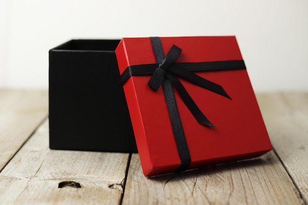 Rote und schwarze Geschenkbox auf Holzhintergrund