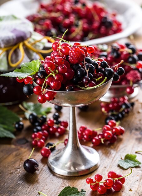 Rote und schwarze Johannisbeere in rustikaler Schüssel auf dem Küchentisch.