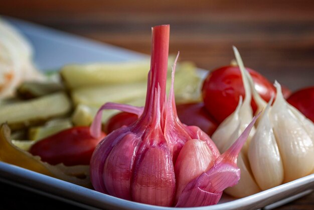 Foto rote und weiße eingelegte knoblauch auf einem teller mit gurken hausgemachte zubereitungen für den winter closeup