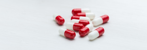 Rote und weiße Pillen auf einem weißen Tischhintergrund mit Kopienraumkonzept der Medikation von Vitaminen