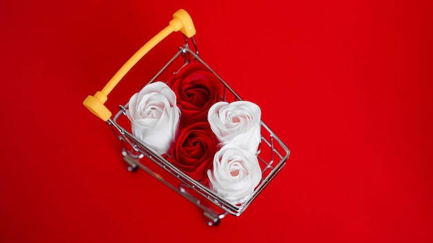 Rote und weiße rosen blühen auf einkaufswagen auf rot