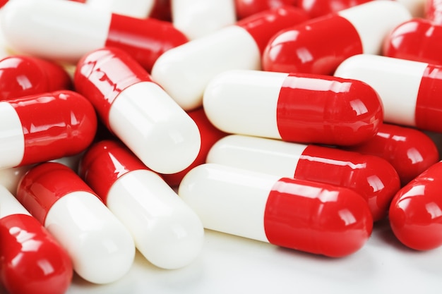 Rote und weiße Tabletten auf weißem Hintergrund mit freiem Speicherplatz. Ansicht von oben