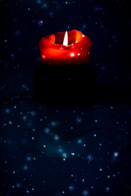Rote Urlaubskerze auf dunklem, funkelndem, schneiendem Hintergrund Luxus-Branding-Design für Weihnachten, Silvester und Valentinstag