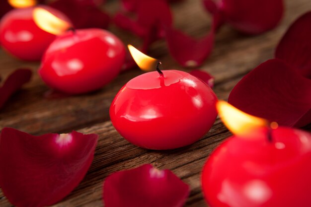 Rote Wachskerzen umgeben von Rosenblättern