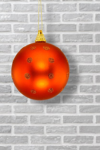 Rote Weihnachtskugel und eine Wand im Hintergrund.