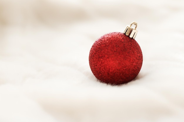 Rote Weihnachtskugeln auf weißem, flauschigem Pelzhintergrund Luxus-Winterurlaub-Design-Hintergrund