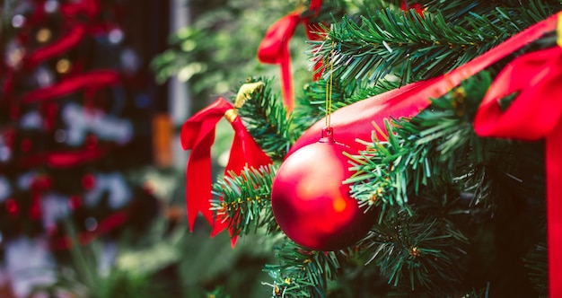 Rote Weihnachtskugeln und rotes Schleifenband schmücken den Weihnachtsbaum Weihnachtshintergrund