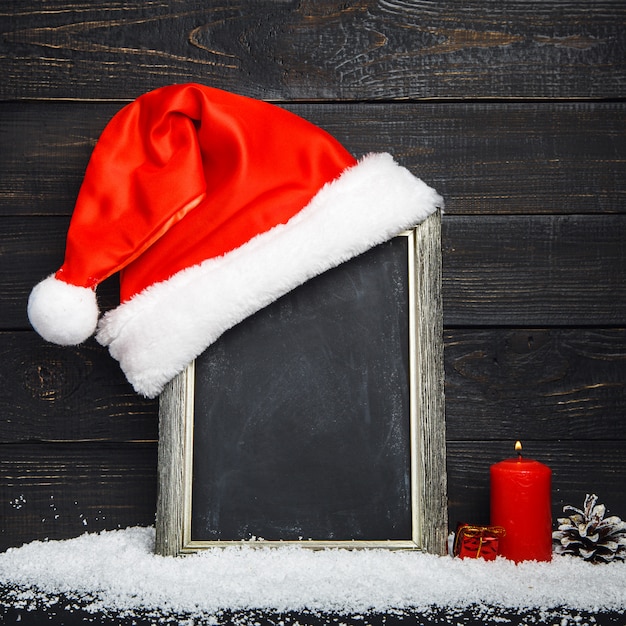 Rote Weihnachtsmütze auf der Tafel mit Schnee