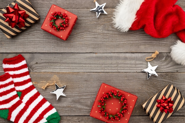 Rote Weihnachtsmütze, Geschenkboxen und Socken auf altem Holz. Weihnachtswohnung lag