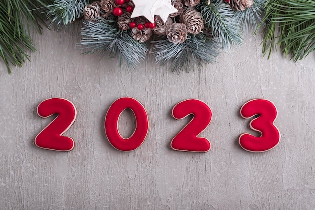 Rote Zahl 2023 aus Lebkuchen und Weihnachtskranz Gute Neujahrsstimmung Hellgraue Wand im Hintergrund