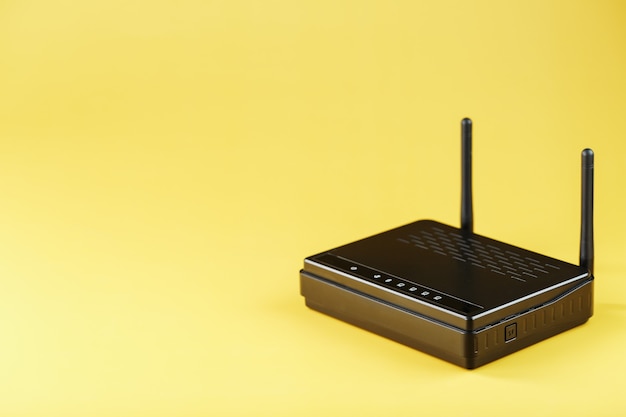 Roteador wifi em preto em um fundo amarelo com espaço livre