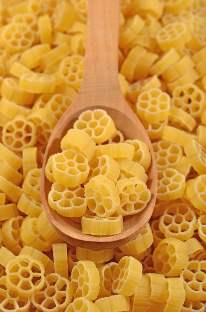 Rotelle de pasta italiana cruda en una cuchara de madera