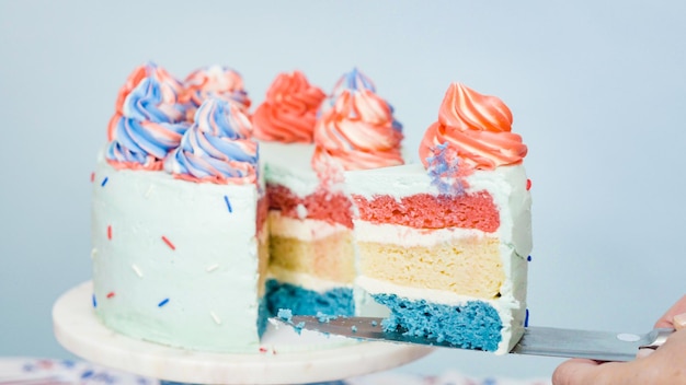 Roten, weißen und blauen dreischichtigen Kuchen schneiden.