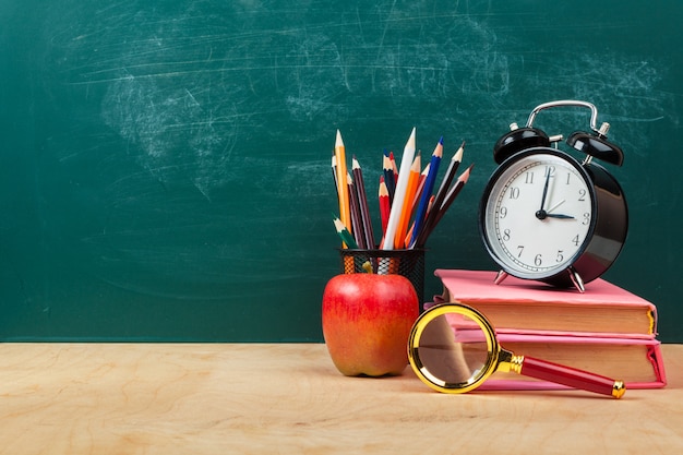 Roter Apfel auf einem Stapel von Büchern, Papier und Bleistift auf dem Schreibtisch