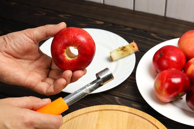 Roter Apfel mit geschnittenem Kern in der Hand und Spezialmesser zum Entfernen von Kernen aus Früchten