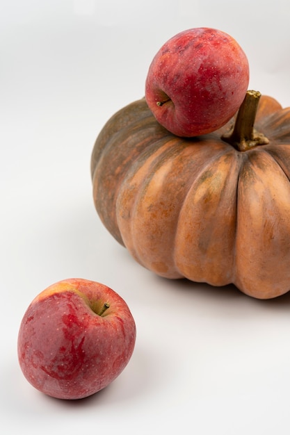 Foto roter apfel mit kürbis auf weißem hintergrund, nahaufnahme. selektiver fokus, makro, herbsternte