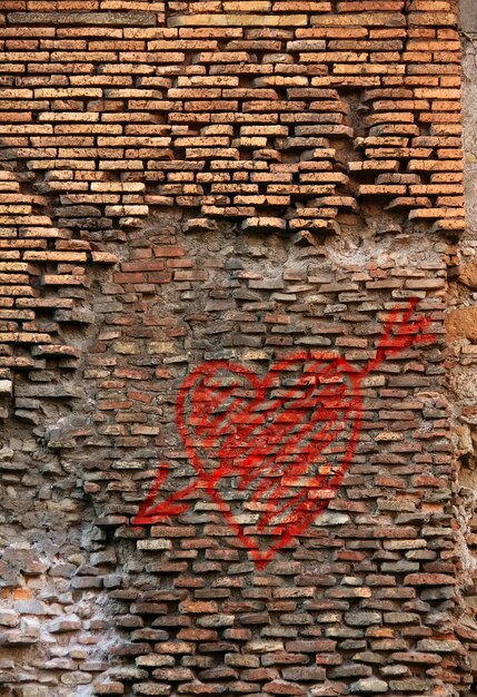 Roter Backsteinwandbeschaffenheit-Schmutz-Hintergrund mit Herzgraffiti