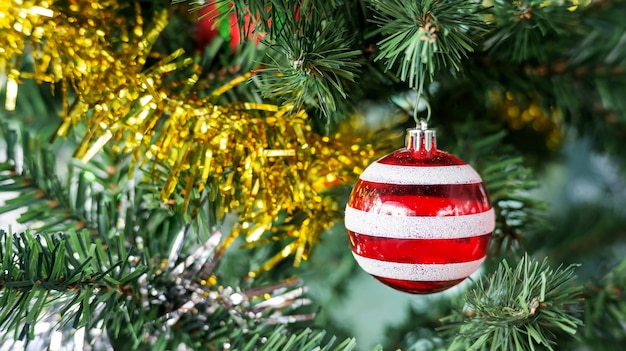 Roter Ball, der an einem Weihnachtsbaum hängt.