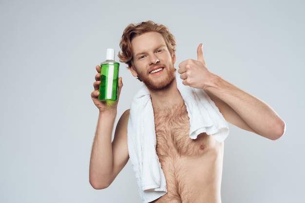 Roter behaarter Mann, der mit Flasche Mundwasser aufwirft