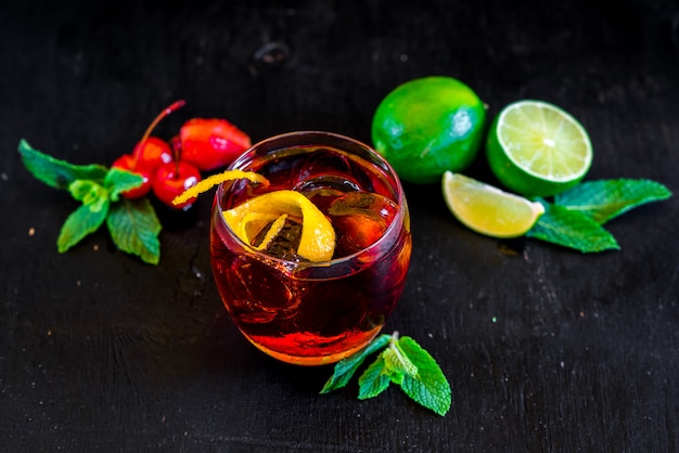 Roter Cocktail mit Eis und Orange auf schwarzem Hintergrund