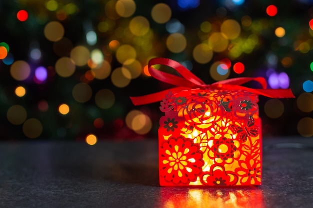 Roter durchbrochener Kasten mit einem Geschenk unter dem horizontalen Weihnachtsbaum