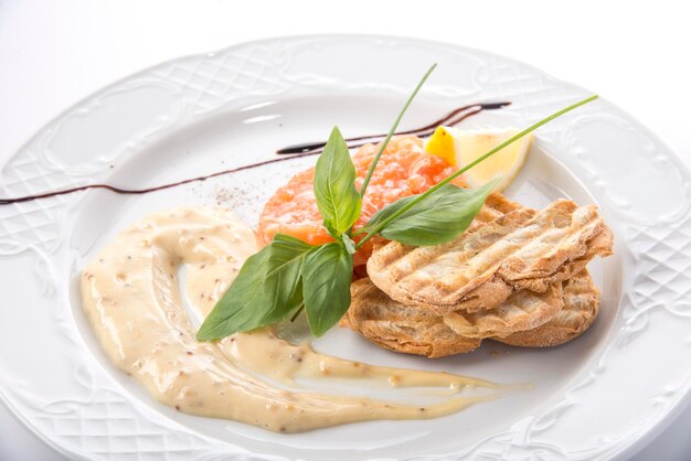 Roter Fisch und Kaviar-Tartar, serviert auf einem Teller mit Brot und Sauce