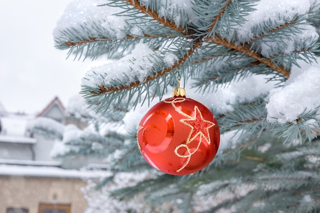 Roter Flitter mit Stern auf einem Weihnachtsbaum unter Schnee draußen