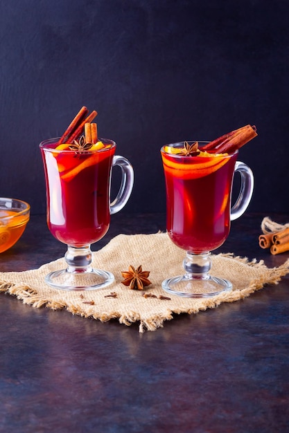 Roter Glühwein auf Burlap Glühwein mit Orangen, Honig, Zimt und Nelken auf dunklem Hintergrund