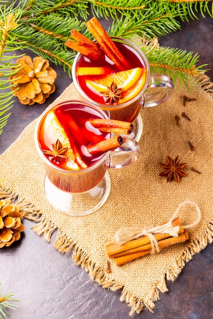 Roter Glühwein und Tannenzweige auf Burlap Glühwein mit Orangen, Honig, Zimt und Nelken