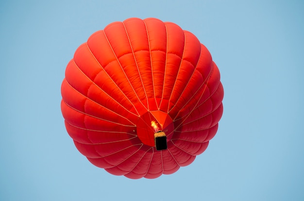 Roter Heißluftballon in einem klaren blauen Himmel.